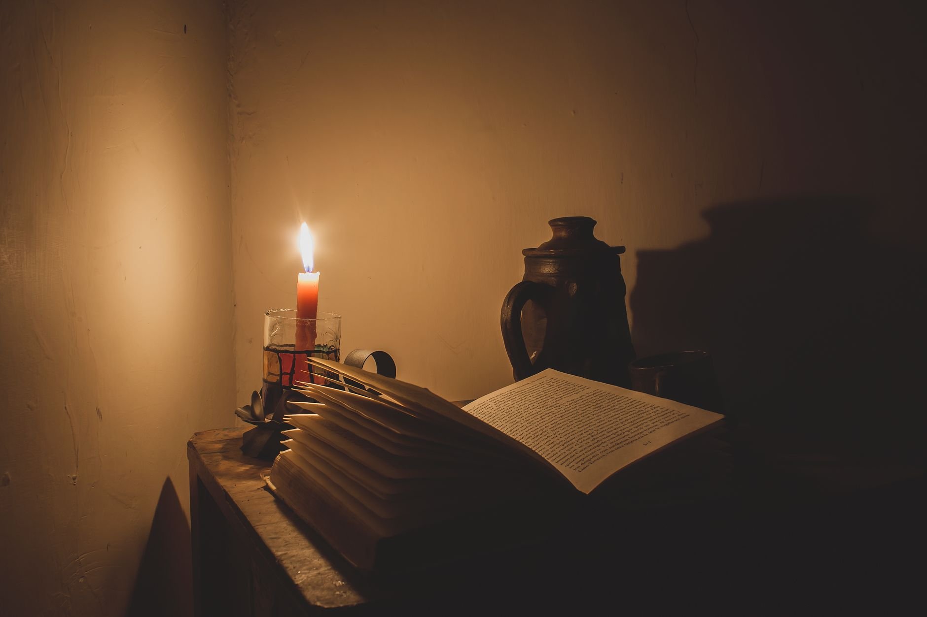 A moody candlelit scene featuring an open book, subtle shadows enhancing a warm, vintage ambiance.